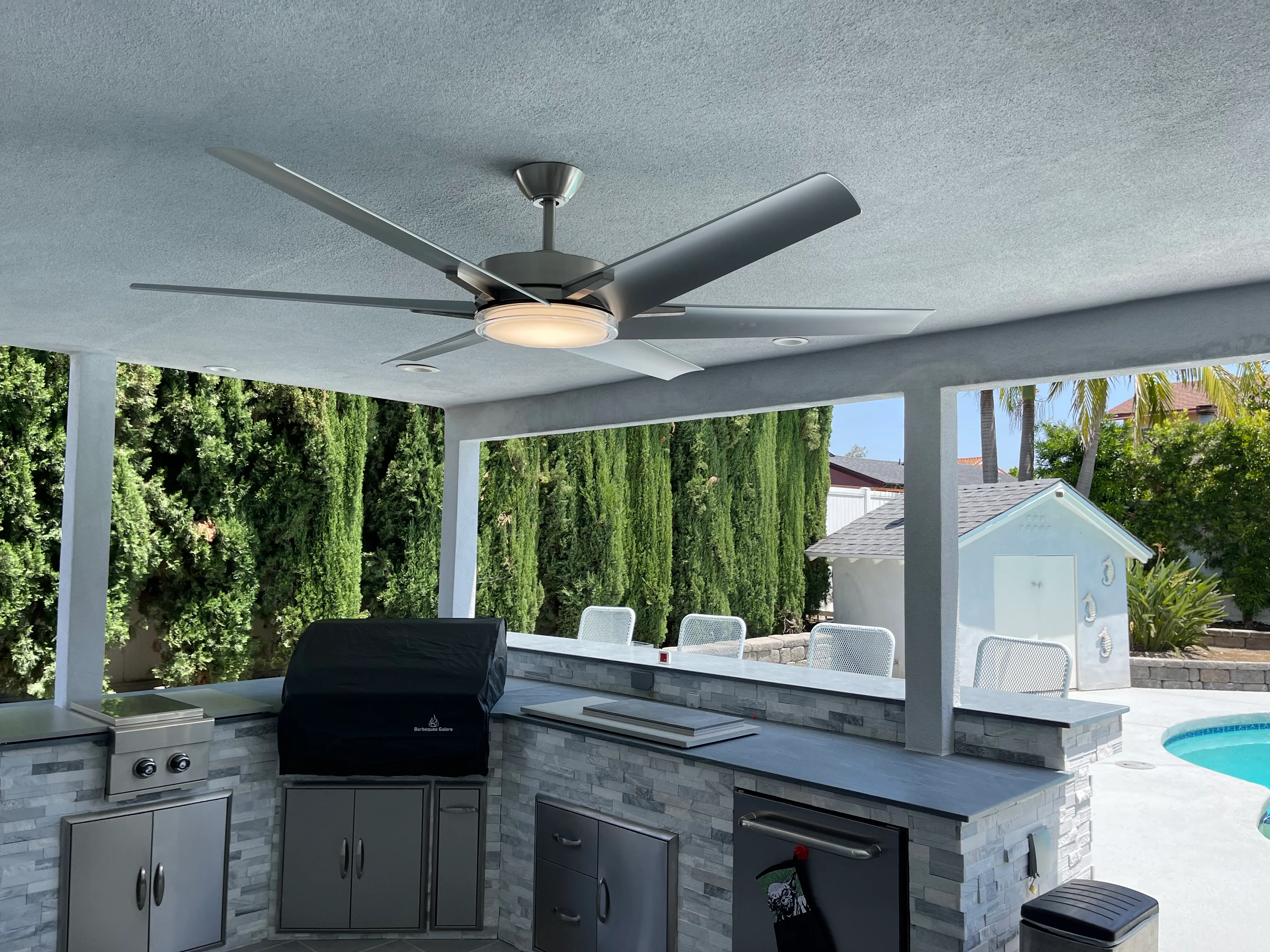 Ventilador de techo con luz instalado en un patio cubierto junto a la alberca